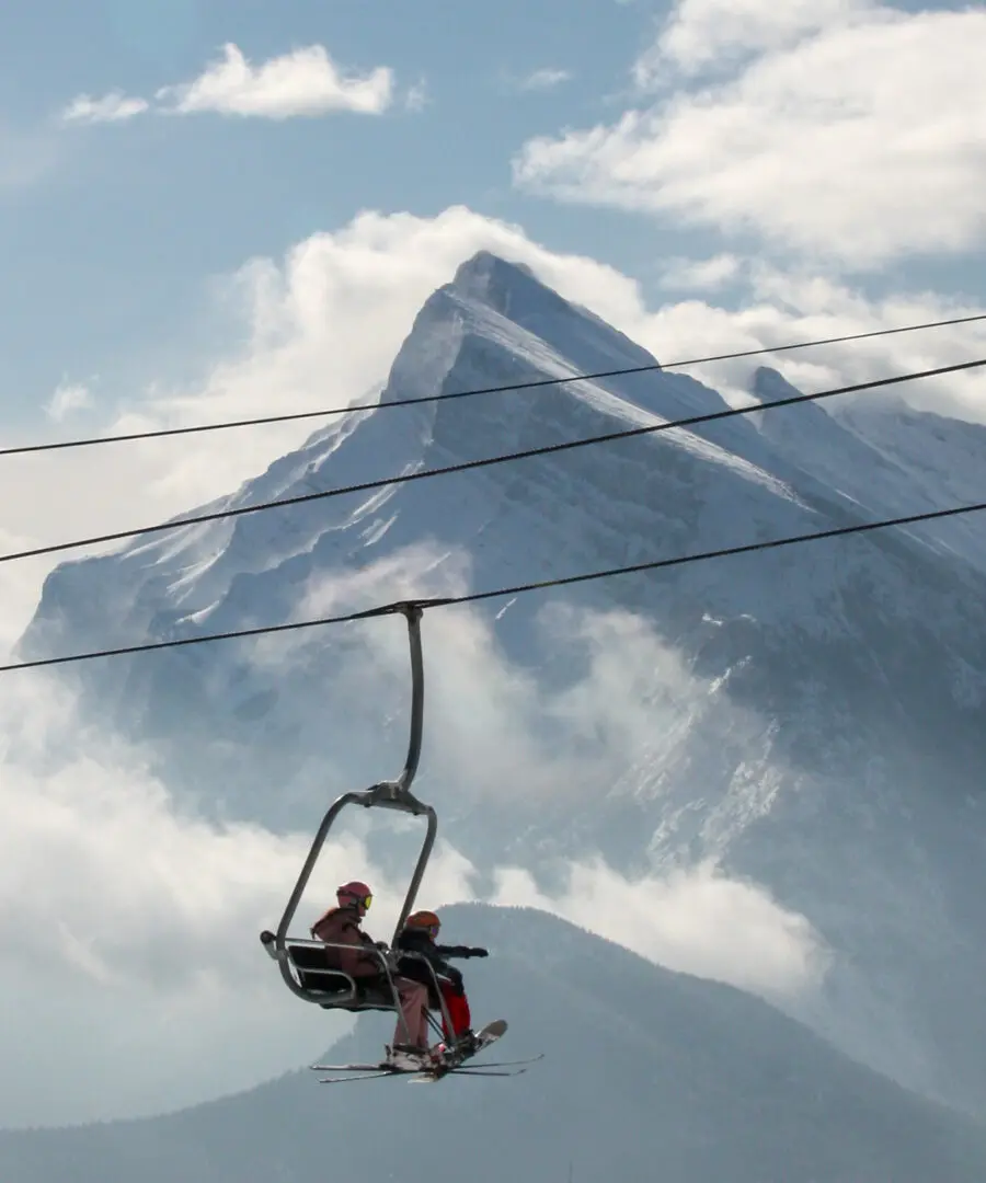 A skier in red rides a chairlift above Banffs snowy alpine peaks safely.